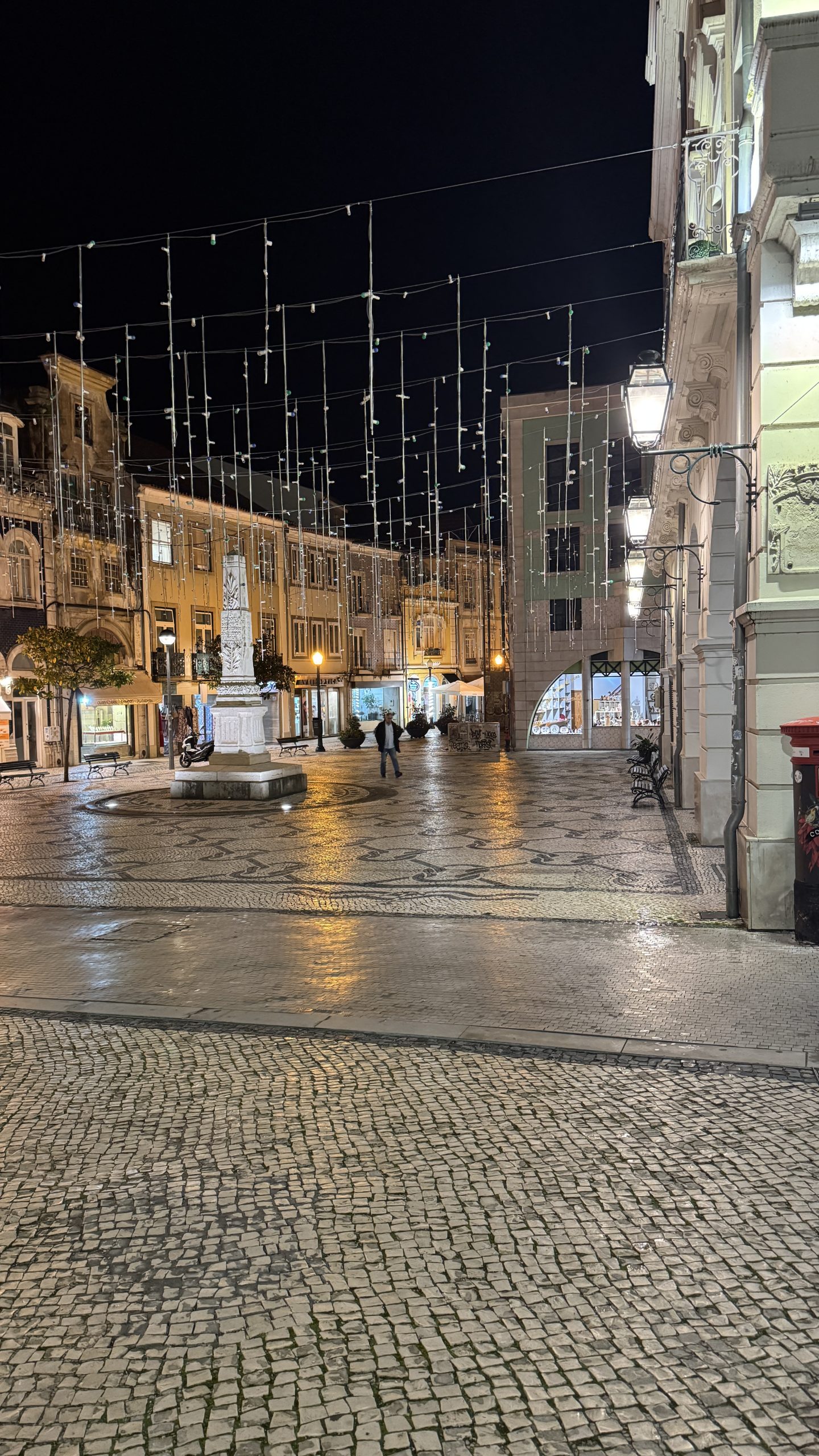 Aveiro historic square at night with lights, cobblestone pavement and people walking